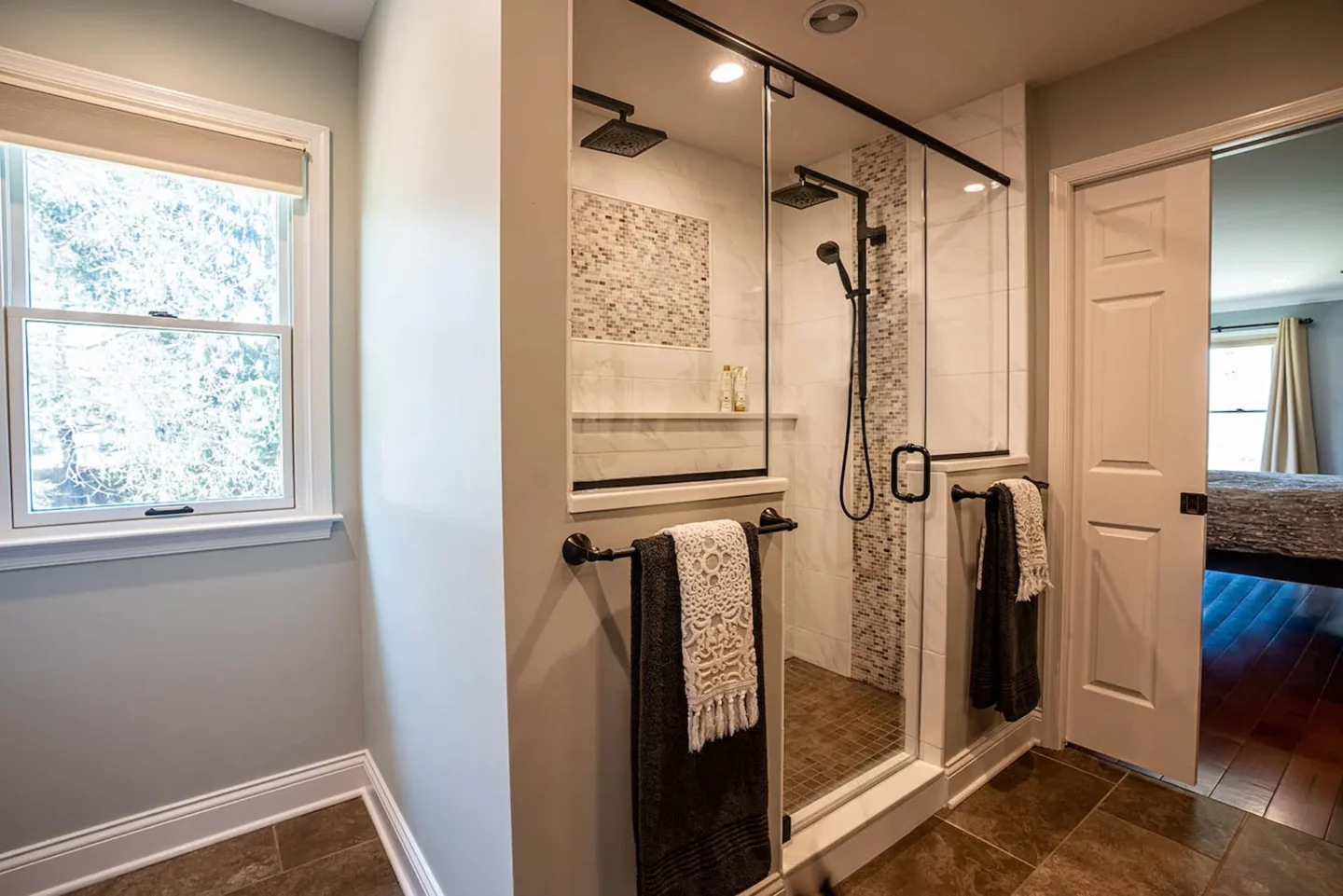 Glass enclosed shower area with two towel hangers in North Wales bathroom