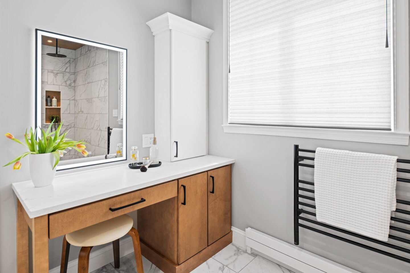 Dedicated makeup vanity area with quartz countertop, maple cabinetry, and natural light in a modern primary bathroom remodel.