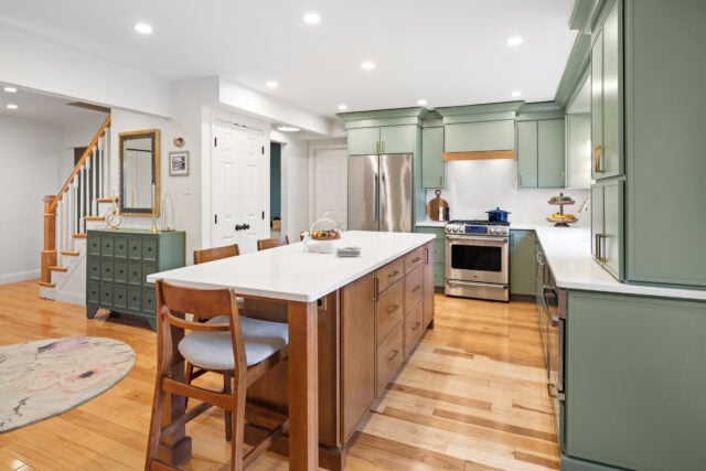 Painted kitchen cabinets paired with stained wood island and light countertops
