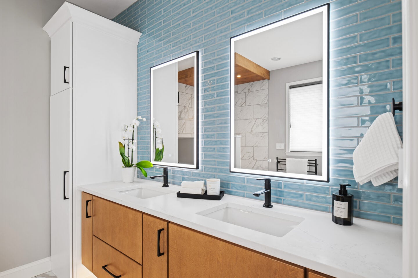 Close-up of floating maple vanity with quartz countertop, under-mount sink, and blue subway tile in a contemporary bathroom remodel.