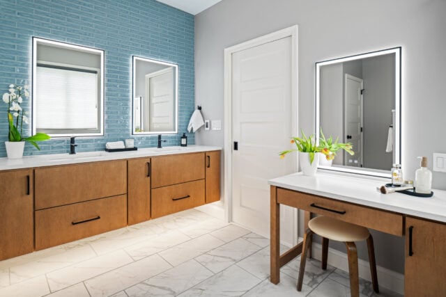 Contemporary primary bathroom featuring floating vanity, blue subway tile accent wall, quartz surfaces, and dedicated makeup station.