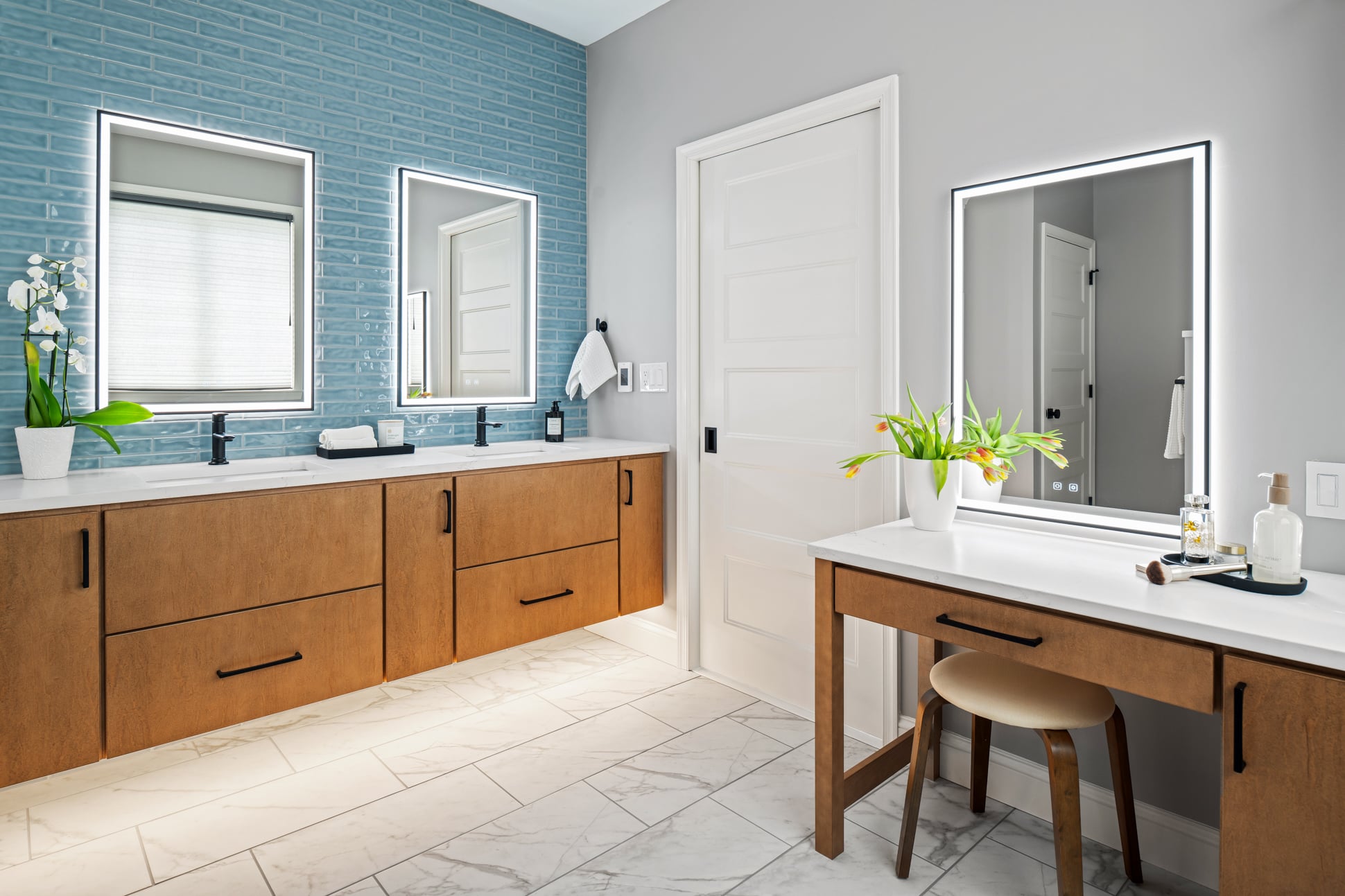 Contemporary primary bathroom featuring floating vanity, blue subway tile accent wall, quartz surfaces, and dedicated makeup station.