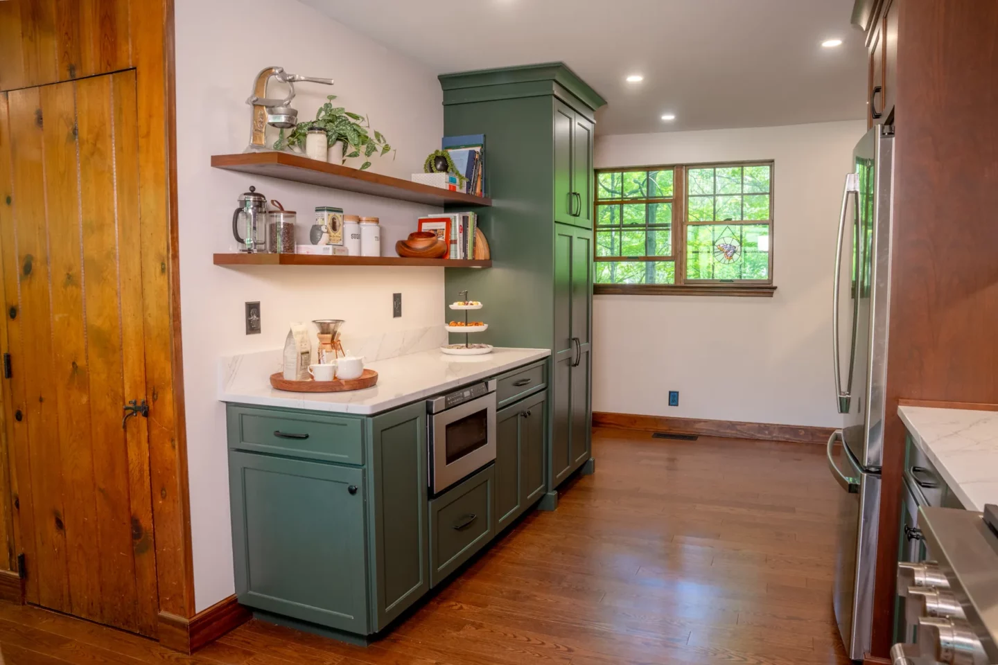 Custom kitchen with Olympic Green base cabinets, cherry upper cabinets, and natural light from enlarged windows.