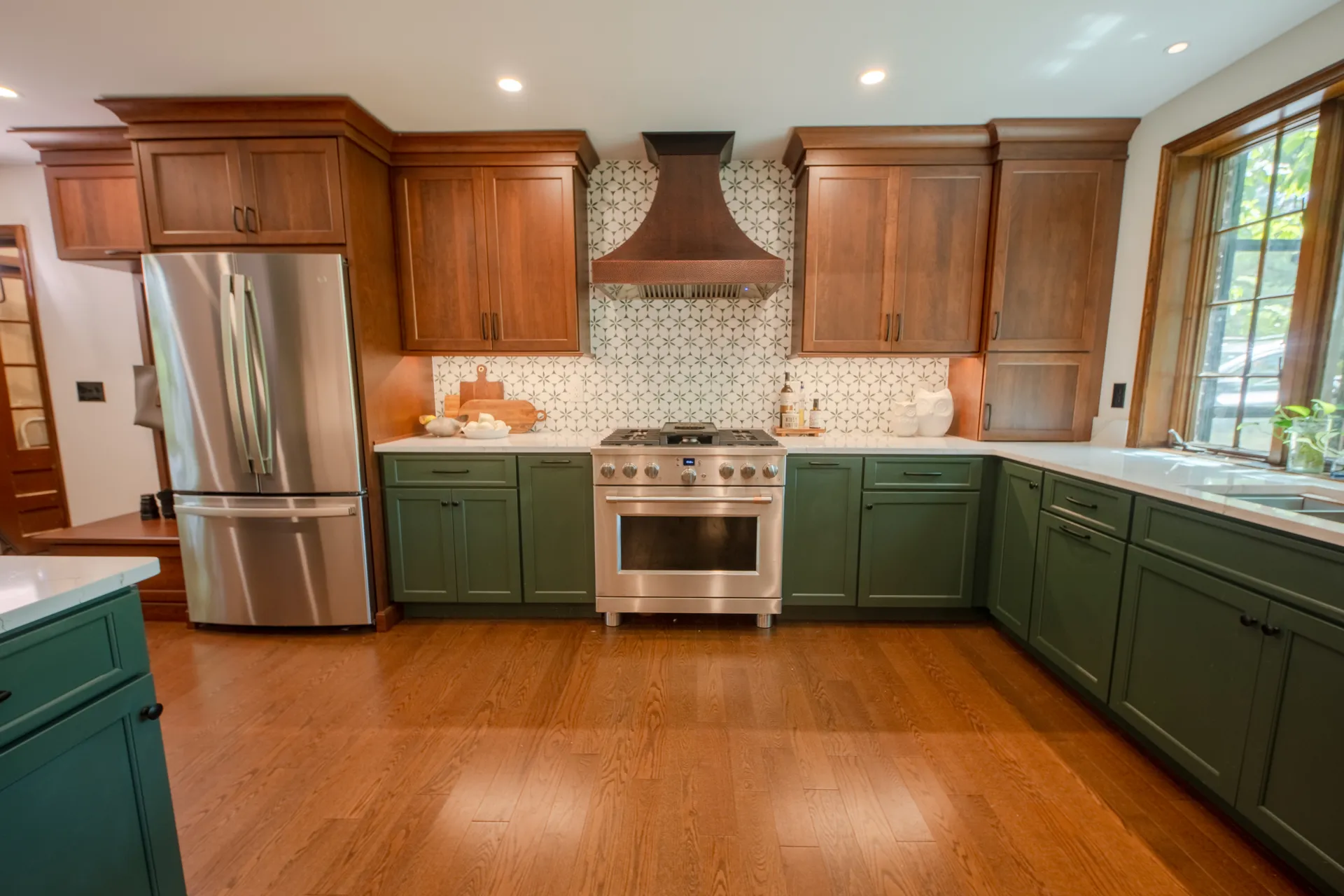 Custom kitchen combining Olympic Green cabinetry, cherry wood cabinets, quartz countertops, and a copper range hood