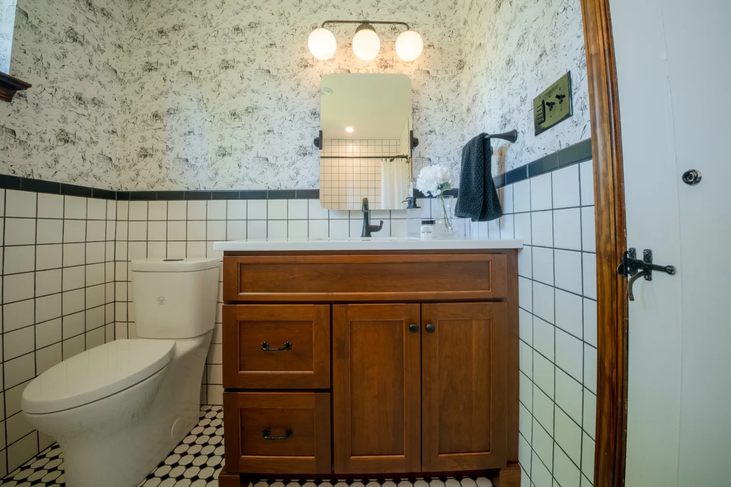 Hall bathroom remodel with soaking tub, classic white tile, and black accent border.