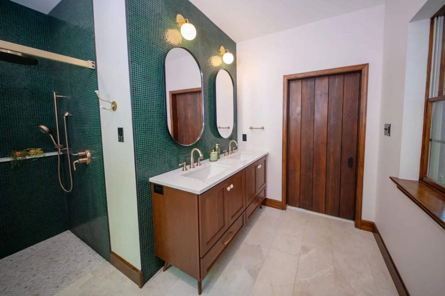 Primary bathroom with custom cherry vanity, marble flooring, and bottle-green glass tile accents