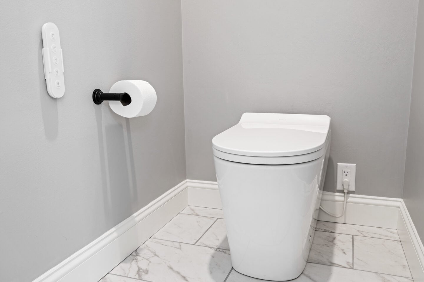 Automated toilet with integrated bidet beside marble-look porcelain flooring in a modern primary bathroom remodel with minimalist detailing.
